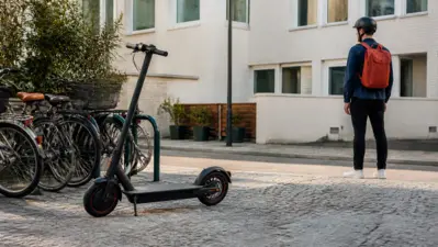 Enkelt el-løbehjul til pendling parkeret ved cykelstativer