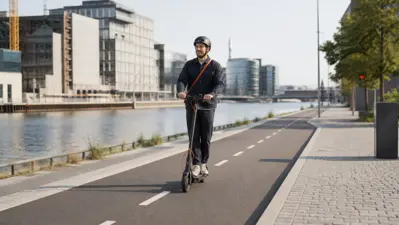 Voksen med hjelm kører el-løbehjul i en afmærket cykelbane